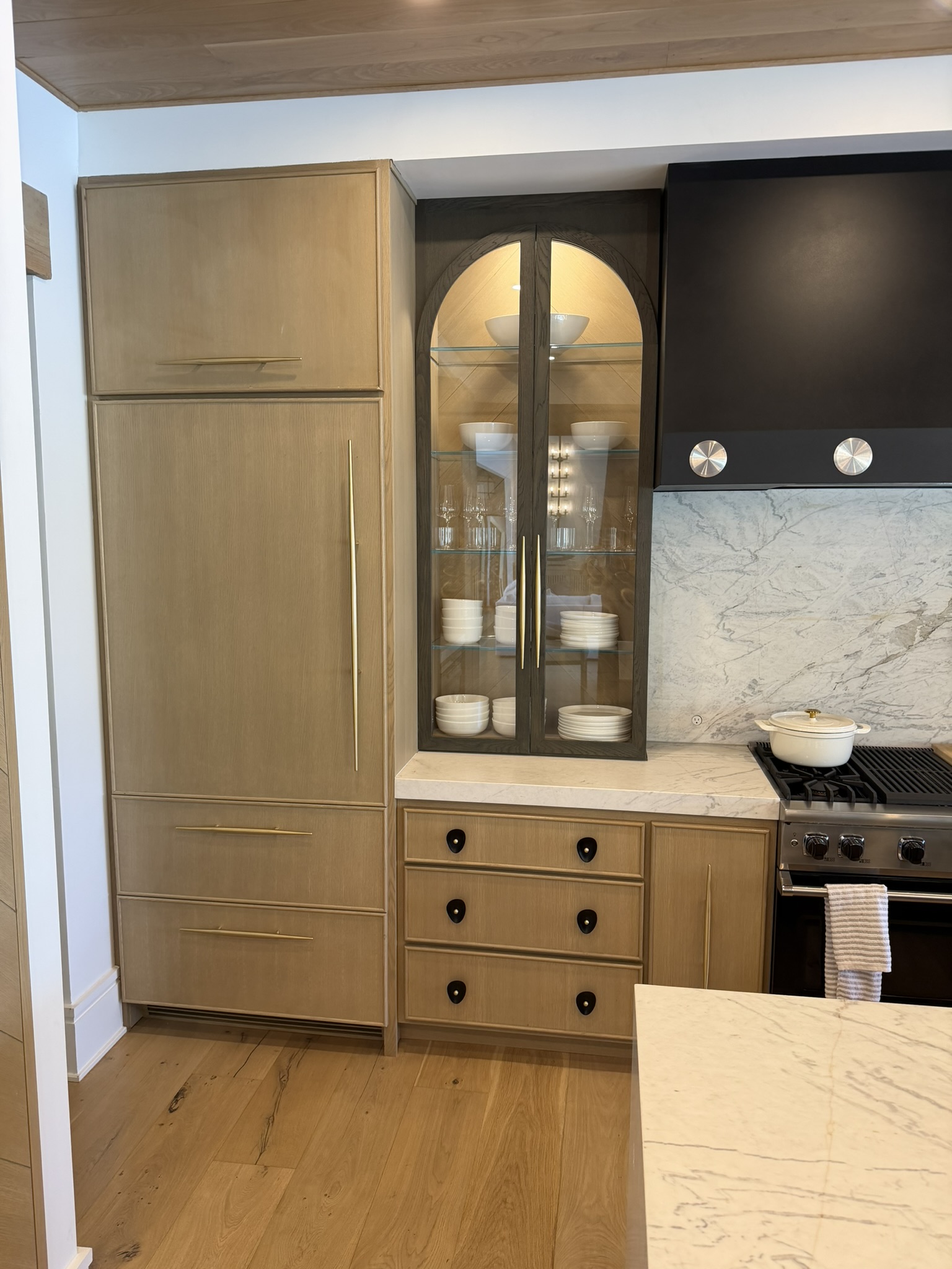 Kitchen with arched glass display cabinet and oak cabinetry