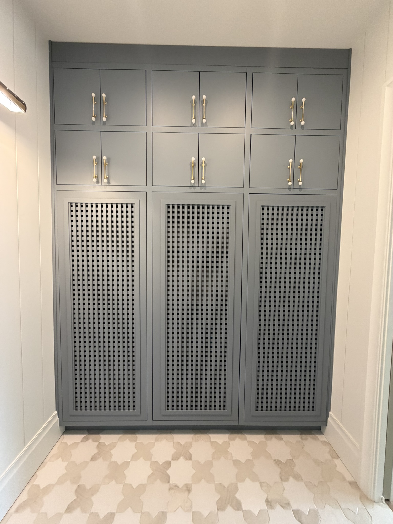 Custom grey painted cabinetry with lattice doors and brass hardware