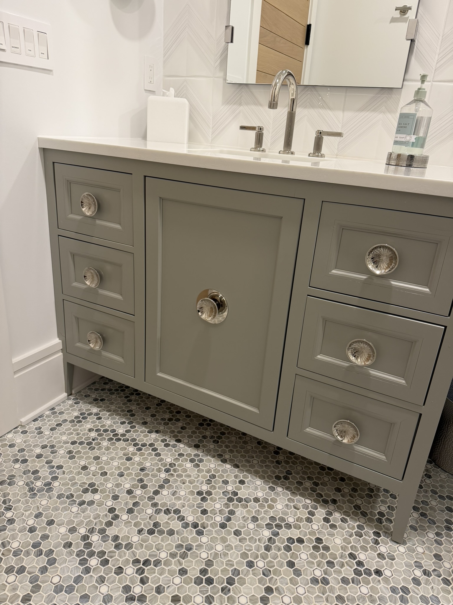 Grey painted vanity with mosaic tile floor and chrome hardware